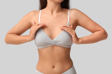 Gri arka planda sütyenli genç bayan, yakın plan.