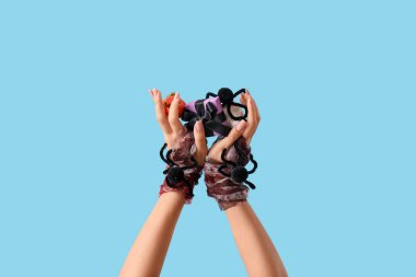 Cadılar Bayramı hediyeli kadın bandajlı eller, mavi arka planda örümcekler ve mini balkabağı.