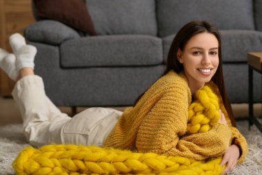 Oturma odasında yerde sıcak sarı ekoseli güzel bir kadın yatıyor.