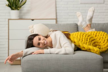 Oturma odasındaki kanepede sıcak sarı ekoseli güzel bir kadın yatıyor.