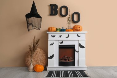 Oturma odasında bej duvarın yanında Cadılar Bayramı dekorlu modern şömine.