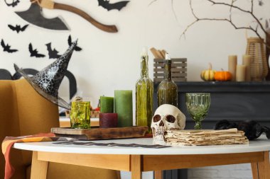 Kafatası, mumlar ve oturma odasındaki sehpanın üzerindeki eski kitap. Cadılar Bayramı dekorasyon konsepti