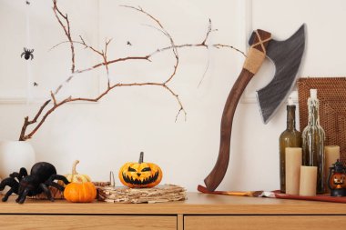 Oturma odasındaki beyaz duvarın yanında Cadılar Bayramı süslemeleri olan çekmeceler.