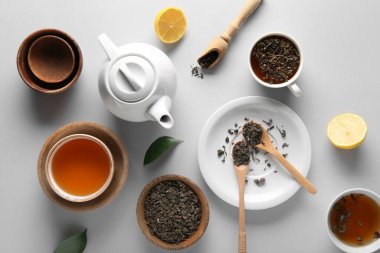Beyaz arka planda çay demliği, kase ve kuru çay yapraklı kompozisyon