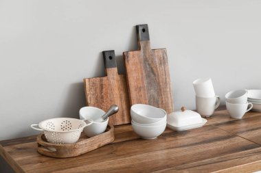 Mutfaktaki ışık duvarının yanındaki tezgahta temiz tabaklarla tahta kesmek.