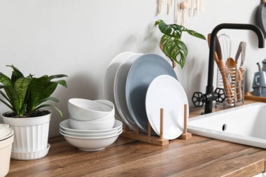 Mutfaktaki ışık duvarının yanındaki tezgahta bitki olan temiz tabaklar.