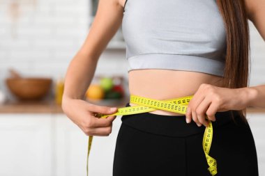 Mutfakta belini ölçen genç bir kadın, yakın plan. Diyet kavramı
