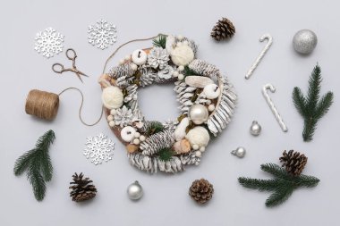 Gri arka planda güzel süslemeleri ve malzemeleri olan Noel çelengi.