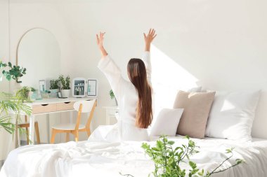 Yatak odasındaki makyaj masasının yanında uzanan genç bir kadın.