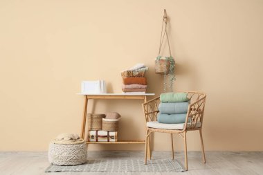 Sandalye ve masa, bej duvarın yanında temiz kıyafetler var.