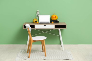 Modern dizüstü bilgisayarı, koltuğu ve kabağı olan işyeri Cadılar Bayramı kutlamaları için dekore edildi.