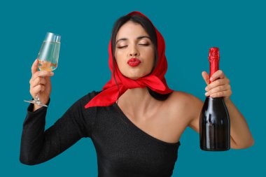 Şişe ve bir kadeh şampanyayla güzel, genç, zarif bir kadın mavi arka planda öpüşüyor.