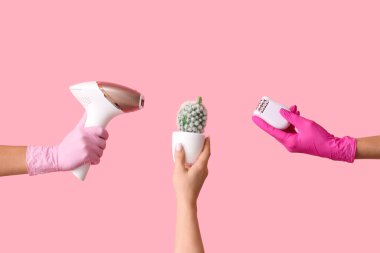 Pembe arka planda modern fotoepilatör, kaktüs ve epilatör olan kadın elleri. Yasaklama kavramı