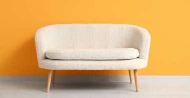 Turuncu duvarın yanındaki rahat beyaz kanepe.