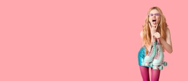 Pembe arka planda eski model patenlerle yüzünü buruşturan genç kadın.