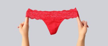 Gri arka planda seksi kırmızı külotlu kadın elleri