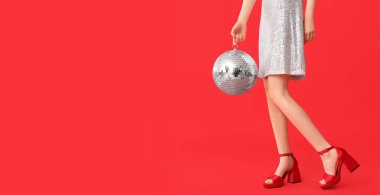 Kırmızı arka planda disko topu olan güzel genç bir kadın.