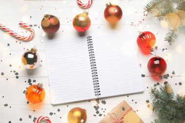 Beyaz ahşap arka planda Noel süsleri olan boş bir defter