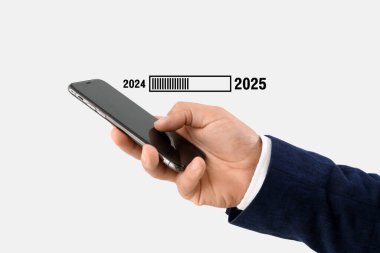 Hand of businessman using mobile phone and status bar with year 2024 and 2025 on light background clipart