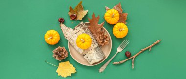 Yeşil zemin üzerinde kabak, ağaç kabuğu ve koni ile sonbahar masa ayarı