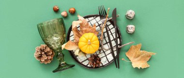 Yeşil arka planda balkabağı ve kurumuş yapraklarla sonbahar masası ayarı