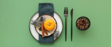 Yeşil arka planda balkabağı, kurutulmuş çiçekler ve baharatlarla sonbahar masası ayarı