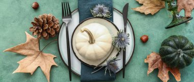 Balkabakları, kurumuş çiçekler ve yeşil arka planda yapraklarla sonbahar masası ayarları