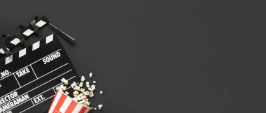 Alkış tahtası, film makarası ve koyu arka planda lezzetli patlamış mısır. Cadılar Bayramı filmi