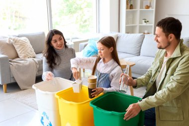 Evde çöpleri geri dönüşüm kutularında sıralayan aile