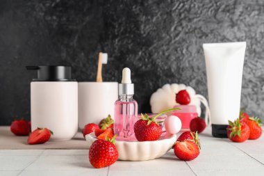 Beyaz fayans üzerinde farklı kozmetik ürünleri ve çilekler