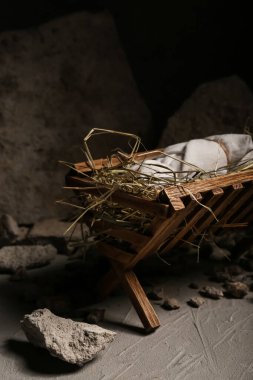 Bebekli ahır, karanlık masada saman ve taşlar