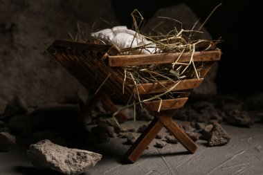 Bebekli ahır, karanlık masada saman ve taşlar