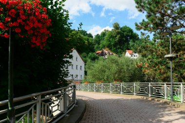 Güneşli bir günde yaya köprüsü ve evler görünüyor