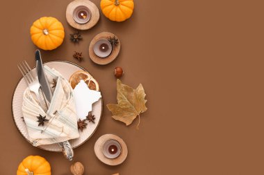 Kahverengi arka planda balkabakları, baharatlar ve yanan mumlarla sonbahar masası ayarları