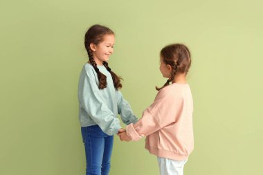 Sweatshirt 'lü şirin kızlar yeşil arka planda el ele tutuşuyorlar.