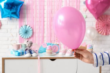 Balonlu ve dekorasyonlu bir kadın eli beyaz tuğlalı arka planda. Cinsiyet ortaya çıkan parti kavramı