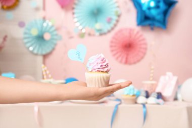 Lezzetli çörekleri ve pembe arka planda süslemeleri olan kadın eli. Cinsiyet ortaya çıkan parti kavramı