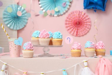 Masada pembe arka planda soru işareti ve süslemeleri olan enfes kekler. Cinsiyet ortaya çıkan parti kavramı