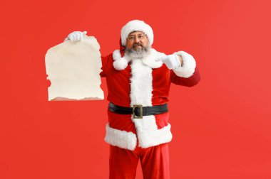 Noel Baba kırmızı arka plandaki boş mektuba işaret ediyor.