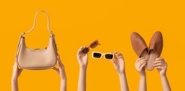 Sarı arka planda güneş gözlüklü, çantalı ve ayakkabılı kadın elleri