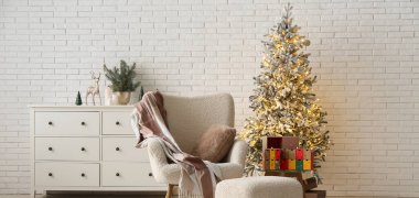 Oturma odasının içinde koltuk, parlayan Noel ağacı ve gelişmekte olan takvim.