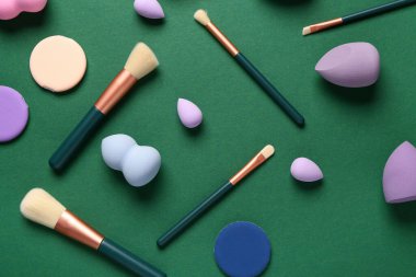 Yeşil arkaplanda makyaj süngerleri ve fırçalar