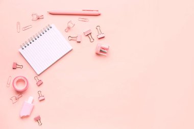 Pembe arka planda farklı kırtasiye malzemesi içeren defter.