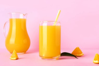Pembe arka planda bir bardak taze portakal suyu.