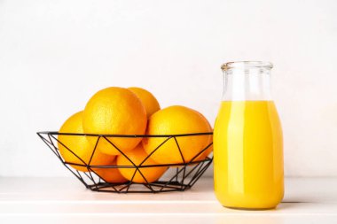 Beyaz ahşap masada bir şişe taze portakal suyu.