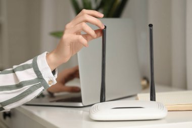 Modern wi-fi yönlendirici, çalışan kadının masadaki bilgisayarı, yakın plan.