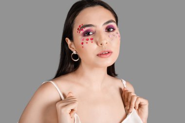 Gri arka planda güzel makyajlı genç bir kadın. Sevgililer Günü kutlaması