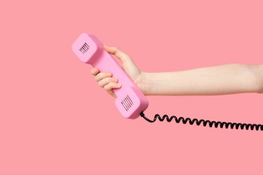 Pembe arka planda retro telefonu olan bir kadın.