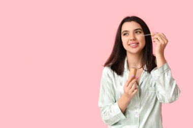 Pembe arka planda gerekli yağ şişesiyle güzel genç bir kadın.