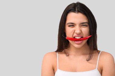 Gri arka planda kırmızı biberli güzel bir kadın.